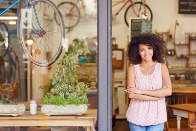51356645 - young mixed race woman smiling, while standing in the door of her cafe with her arms folded proud to be the owner of a small business
